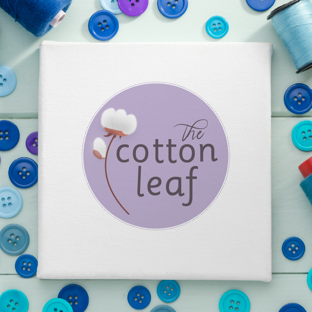 The Cotton Leaf logo printed on canvas surrounded by buttons and thread